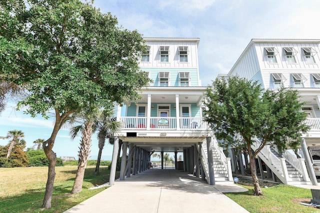 raised beach house with a carport, covered porch, and a front lawn