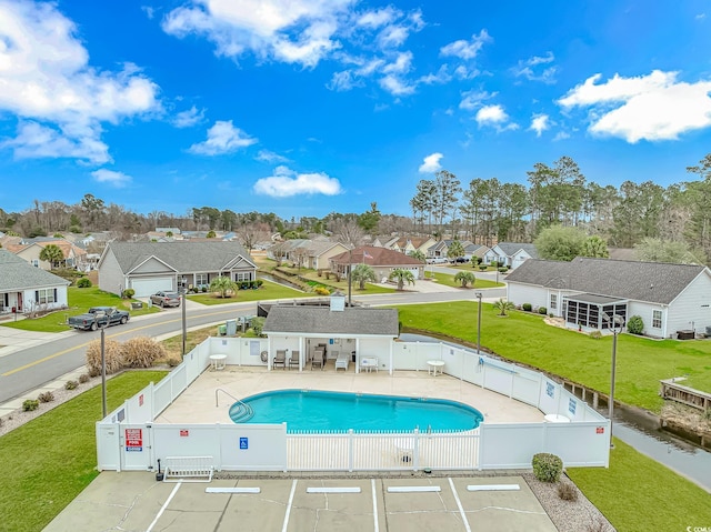 community pool with a patio, a gate, a fenced backyard, and a residential view