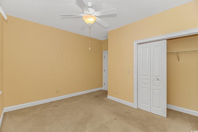 unfurnished bedroom featuring a ceiling fan, a closet, light carpet, and baseboards