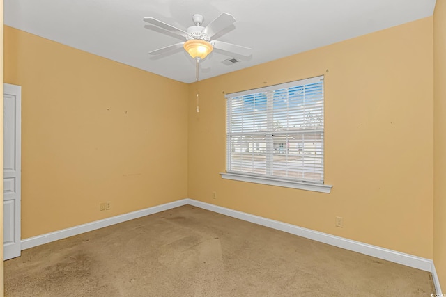 carpeted spare room with ceiling fan, visible vents, and baseboards