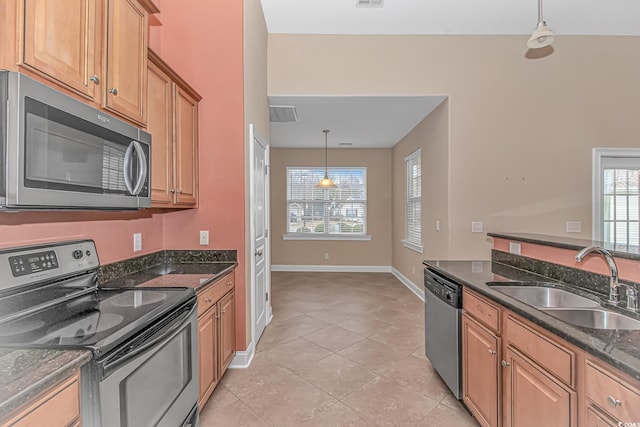 kitchen featuring visible vents, dark stone counters, decorative light fixtures, stainless steel appliances, and a sink