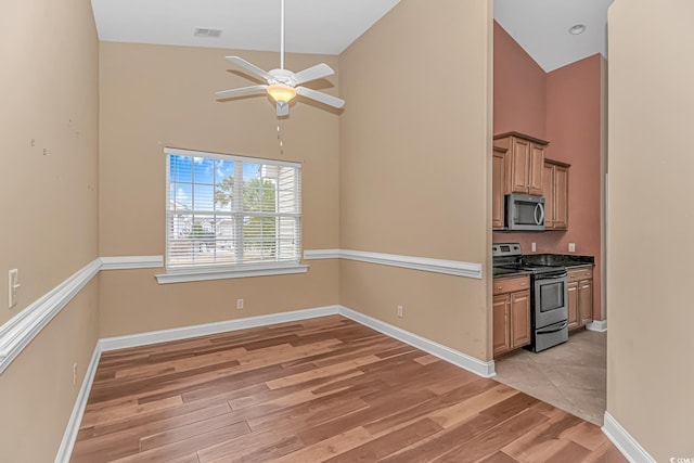 kitchen featuring high vaulted ceiling, stainless steel appliances, visible vents, baseboards, and light wood-type flooring