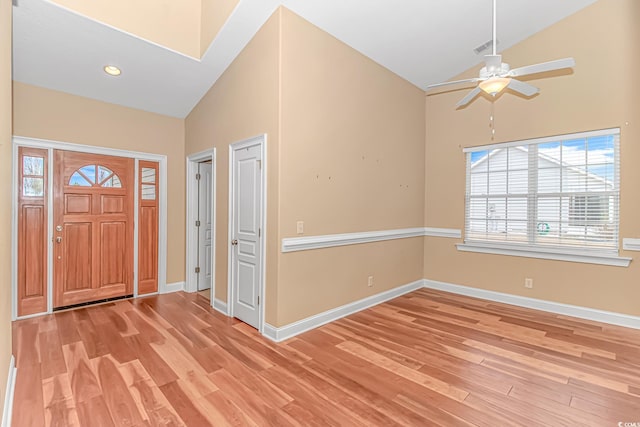 foyer entrance with high vaulted ceiling, visible vents, light wood-style flooring, and baseboards