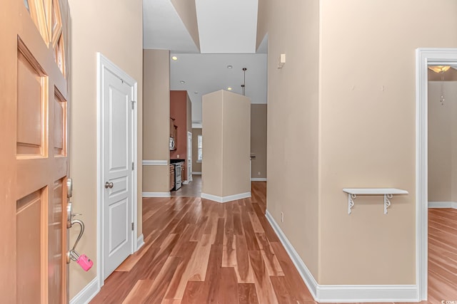 corridor with light wood-type flooring and baseboards