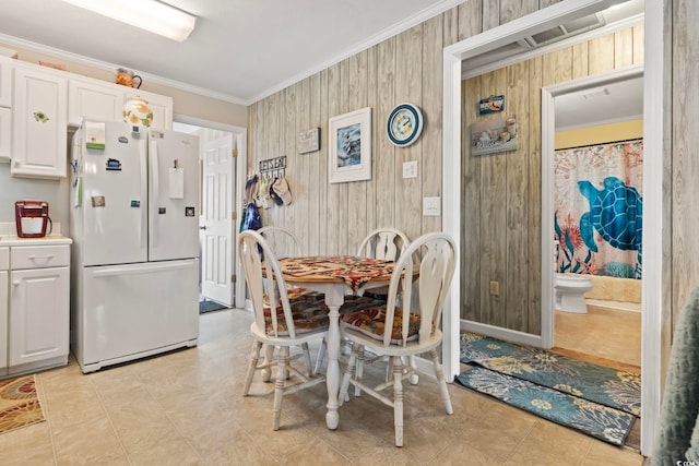dining room with wooden walls, visible vents, ornamental molding, and light tile patterned floors