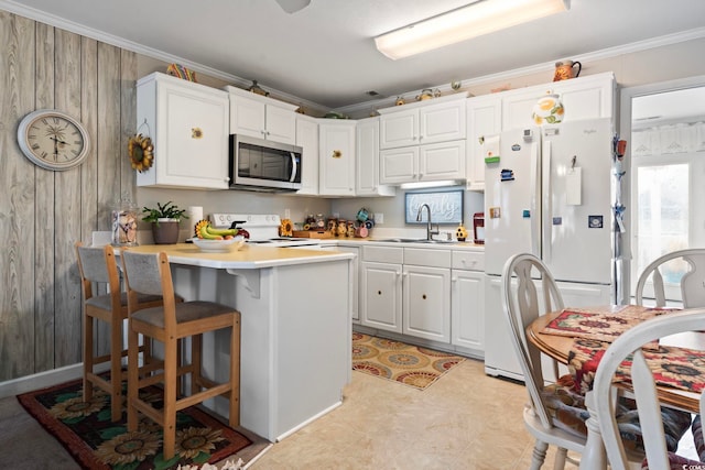 kitchen with a sink, light countertops, white appliances, a peninsula, and white cabinetry