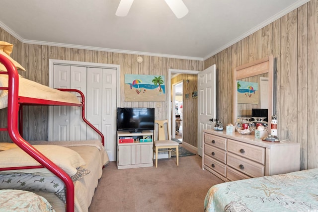 carpeted bedroom featuring crown molding, a closet, wood walls, and a ceiling fan