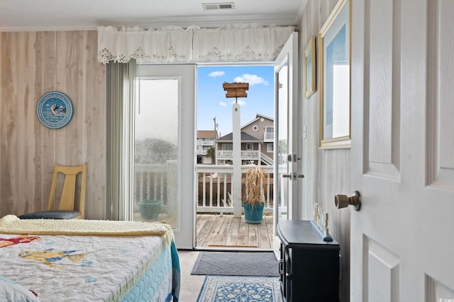 bedroom with ornamental molding, visible vents, multiple windows, and wood walls