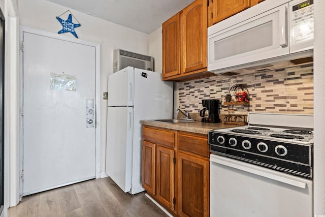 kitchen with white appliances, light hardwood / wood-style floors, sink, and decorative backsplash