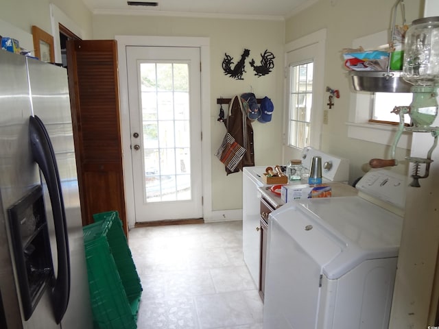 clothes washing area featuring cabinets, ornamental molding, and independent washer and dryer