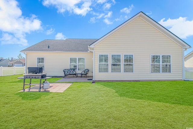 rear view of property with roof with shingles, a patio area, a lawn, and fence