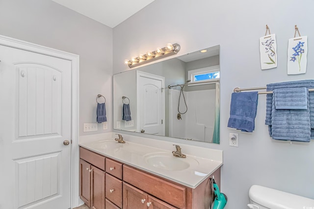 bathroom featuring a shower, a sink, toilet, and double vanity