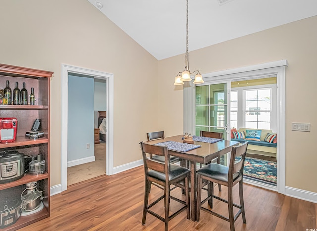 dining area with lofted ceiling, baseboards, a chandelier, and wood finished floors