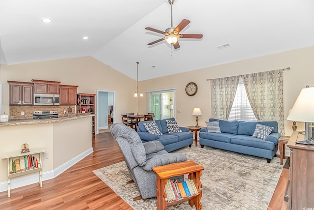 living area featuring lofted ceiling, ceiling fan, light wood-style flooring, visible vents, and baseboards