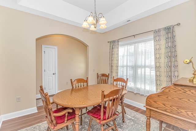 dining area featuring arched walkways, wood finished floors, visible vents, and baseboards