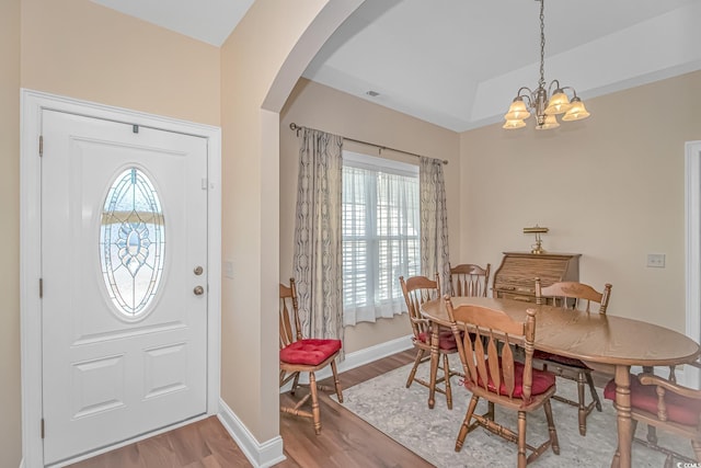 entrance foyer with arched walkways, a notable chandelier, light wood-style flooring, and baseboards