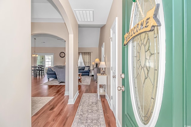 entryway featuring visible vents, arched walkways, wood finished floors, and a chandelier