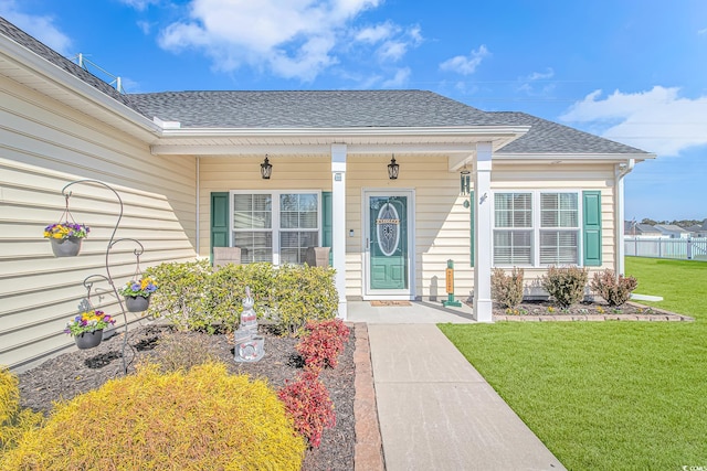 property entrance with a shingled roof, a porch, and a yard