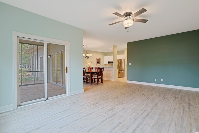 spare room featuring light wood-type flooring and ceiling fan with notable chandelier