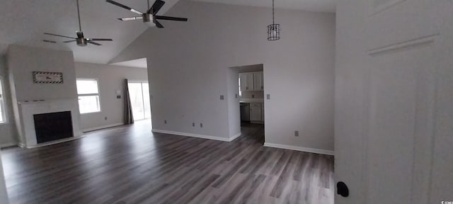 unfurnished living room with a towering ceiling, dark wood-style floors, a fireplace, and baseboards