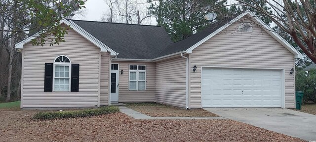 view of front of house with a garage, driveway, and roof with shingles