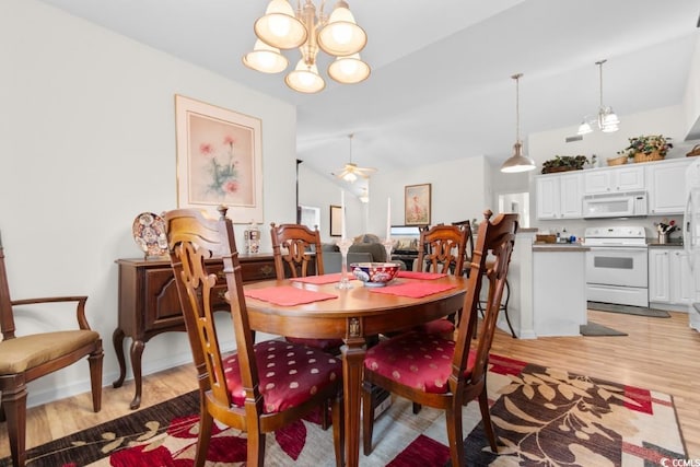 dining space featuring lofted ceiling, light wood-type flooring, and an inviting chandelier