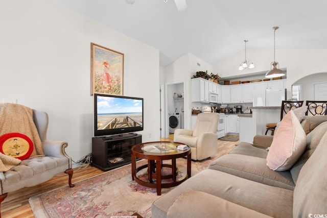 living room with lofted ceiling, washer / dryer, ceiling fan with notable chandelier, and light wood-type flooring