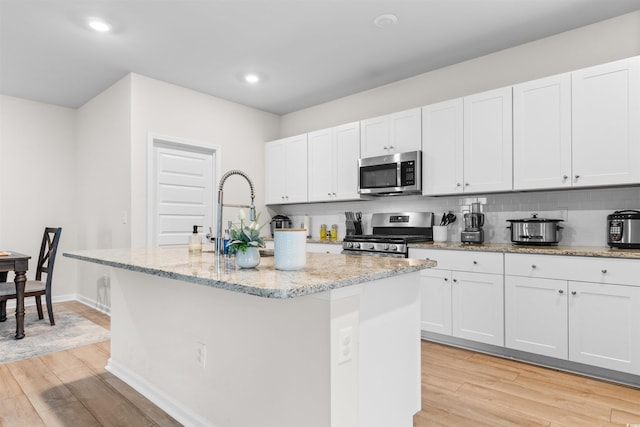 242 Timber Oaks Dr, Myrtle Beach, SC 29588 - kitchen with appliances with stainless steel finishes, a center island with sink, light wood finished floors, light stone countertops, and recessed lighting