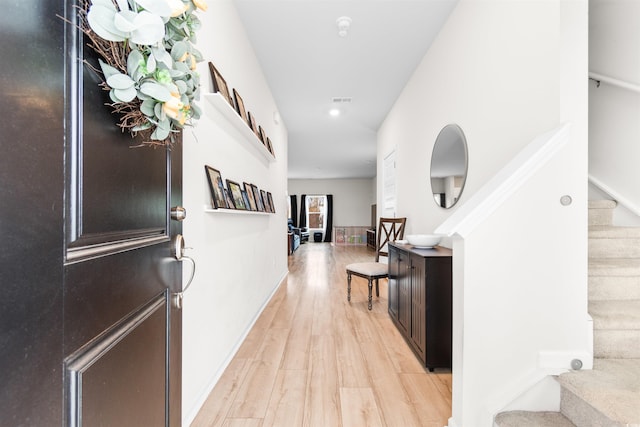 entrance foyer with stairway, light wood-type flooring, visible vents, and baseboards