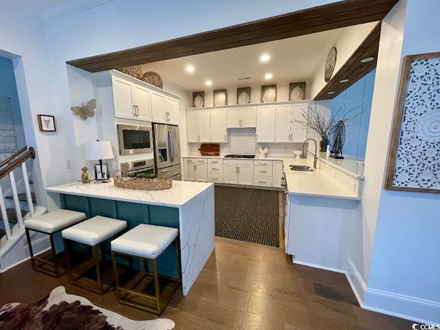 kitchen featuring stainless steel appliances, white cabinetry, sink, and kitchen peninsula