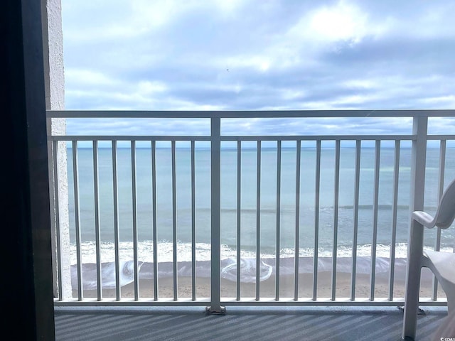 balcony featuring a view of the beach and a water view