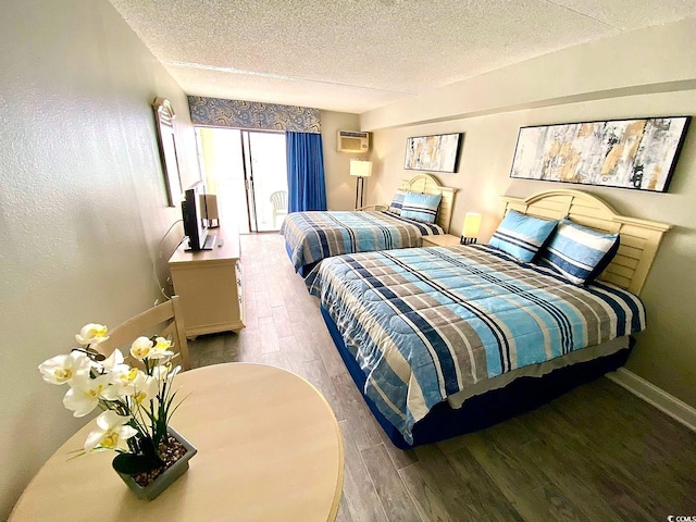 bedroom featuring wood-type flooring, a wall mounted air conditioner, and a textured ceiling