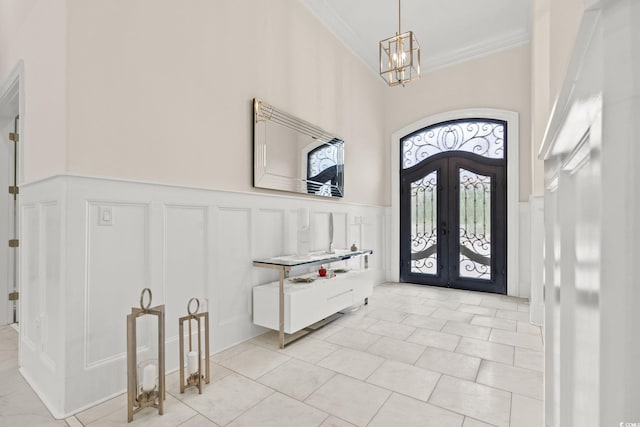 foyer entrance featuring french doors, ornamental molding, a chandelier, and light tile patterned flooring