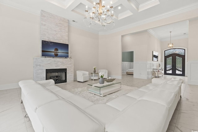 living room with coffered ceiling, a fireplace, french doors, and a chandelier