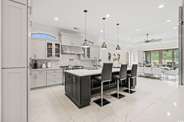 kitchen with white cabinets, an island with sink, pendant lighting, and high end stainless steel range