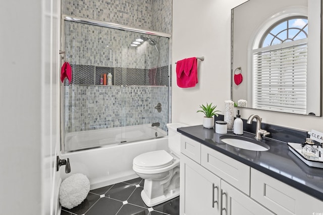 full bathroom with toilet, vanity, bath / shower combo with glass door, and tile patterned flooring