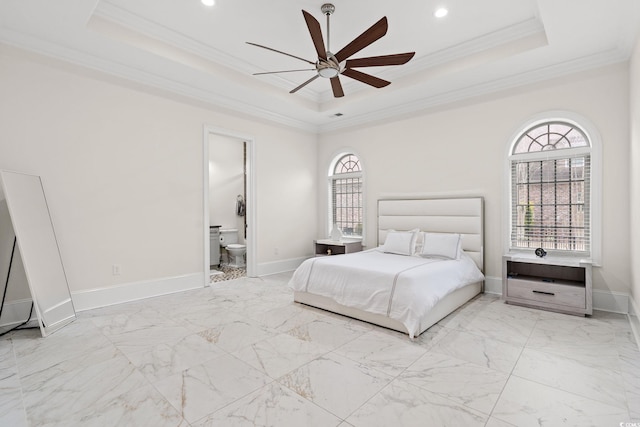 bedroom with crown molding, ceiling fan, ensuite bath, and a tray ceiling