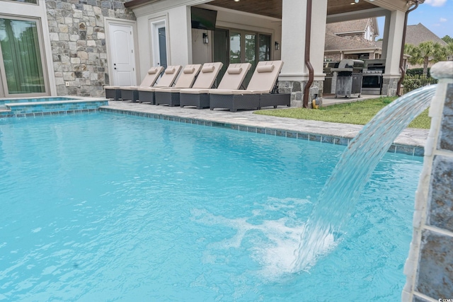 view of pool with pool water feature and grilling area