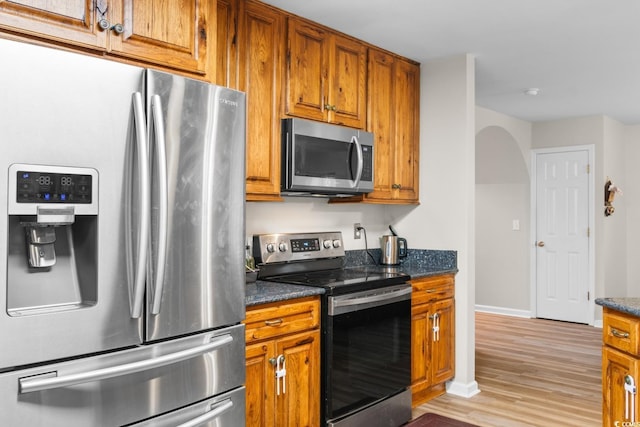 kitchen featuring light hardwood / wood-style flooring, stainless steel appliances, and dark stone counters