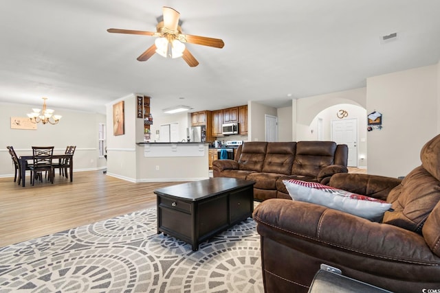 living room featuring ceiling fan with notable chandelier and light hardwood / wood-style floors