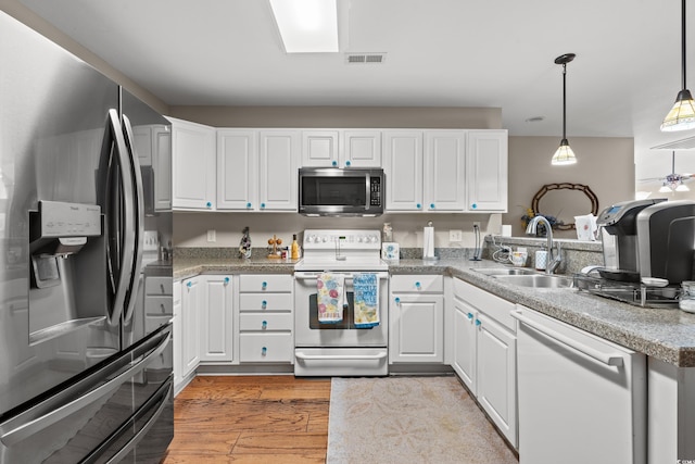 kitchen featuring sink, appliances with stainless steel finishes, white cabinets, and pendant lighting