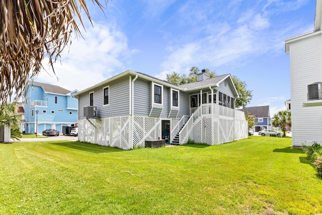 back of property with central AC, a sunroom, a yard, stairway, and a chimney