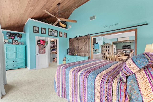 bedroom featuring carpet, a walk in closet, visible vents, a barn door, and wood ceiling