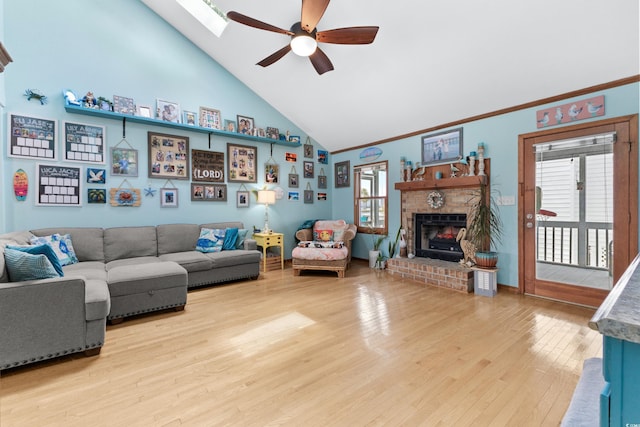 living room with ornamental molding, a ceiling fan, a brick fireplace, wood finished floors, and high vaulted ceiling