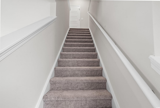 stairway with baseboards and carpet flooring