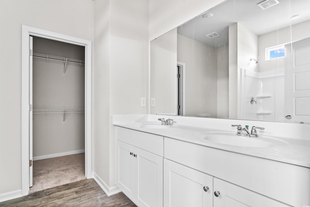 full bath with a spacious closet, double vanity, a sink, and visible vents