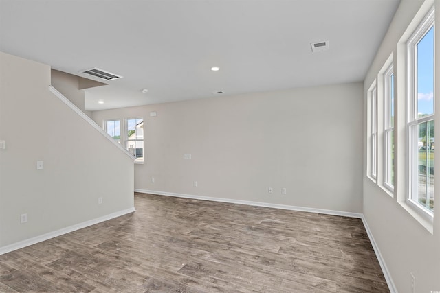 unfurnished room with wood finished floors, recessed lighting, baseboards, and visible vents