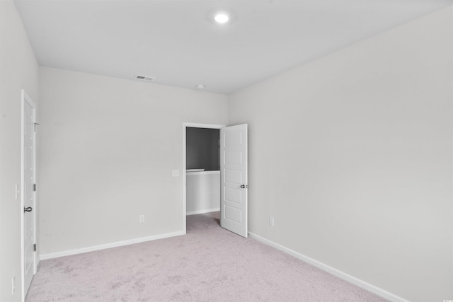 unfurnished bedroom featuring light carpet, baseboards, visible vents, and a spacious closet