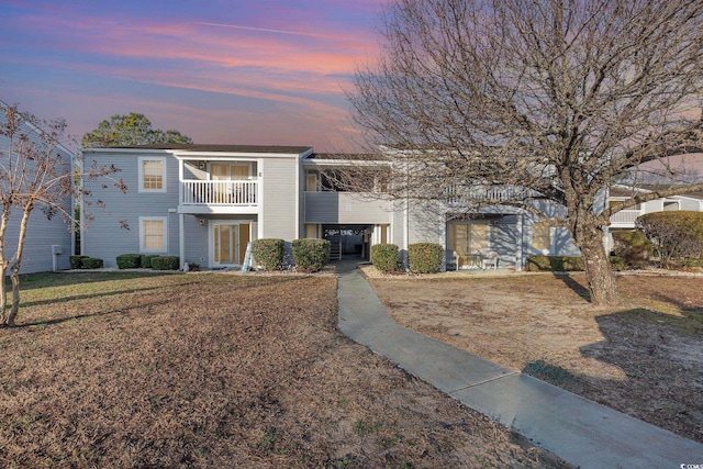 view of front of house featuring a balcony and a yard