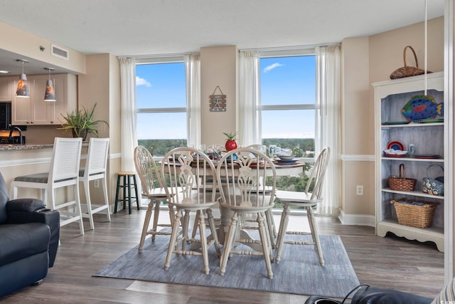 dining area featuring visible vents, a textured ceiling, baseboards, and wood finished floors